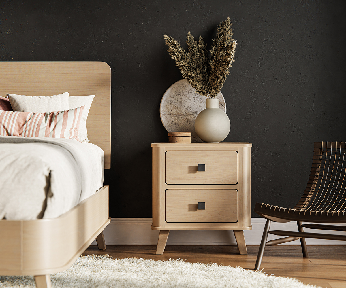 Light wood nightstand beside bed against a dark accent wall.